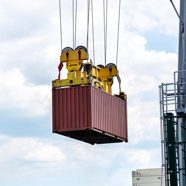 Workers efficiently loading wooden furniture into a Full Container Load (FCL) shipping container, ensuring proper stacking and secure placement with protective padding.