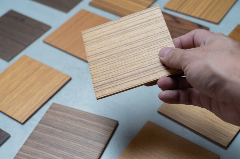 Various types of wood samples, including oak, walnut, and pine, neatly arranged on a workbench for furniture material selection.
