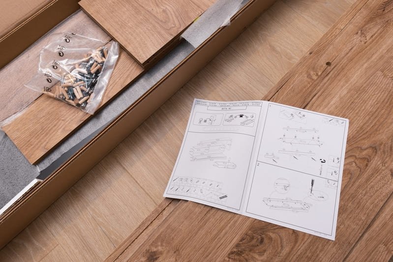 Wood furniture retail package with a securely packed wooden chair inside a branded, reinforced cardboard box, complete with foam padding and assembly instructions.