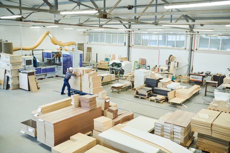 Skilled craftsmen working in a wood furniture workshop, cutting, assembling, and sanding wooden furniture pieces in a well-equipped workspace.