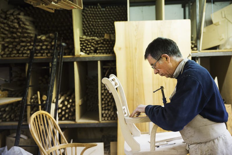 A master craftsman carefully carving intricate details into a wooden furniture piece, showcasing expertise, precision, and dedication to craftsmanship.