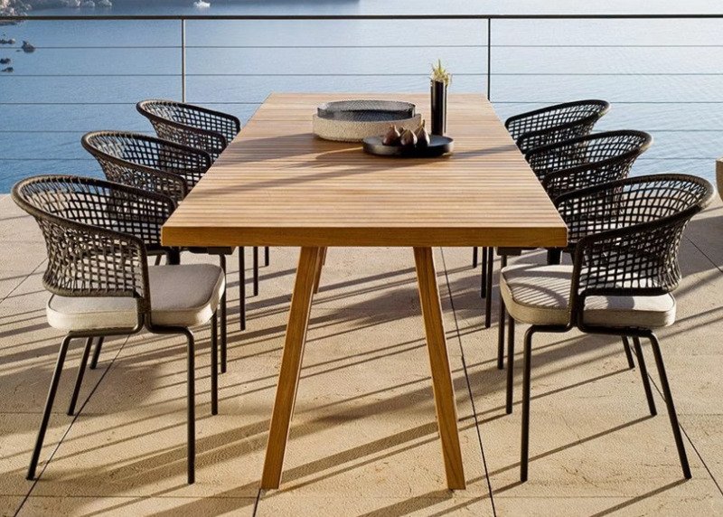 Durable wicker patio set with weather-resistant cushions under a pergola, perfect for outdoor relaxation.