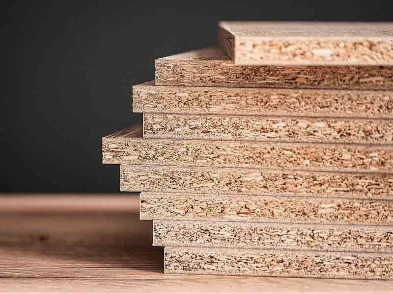 Close-up texture of engineered chipboard showing compressed wood particles – versatile, affordable building material for furniture cores.